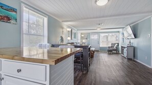 Une cuisine spacieuse dotée d’un îlot central en bois, de meubles blancs et d’un coin repas avec des chaises.