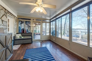 Enjoy the serene view of the lake and surrounding trees from this sunroom, featuring a bench and small table.