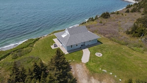 Een huis aan de kust met een schuin dak, een verharde oprit en een gazon.