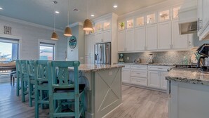A modern kitchen with white cabinetry, a central island, and pendant lighting.