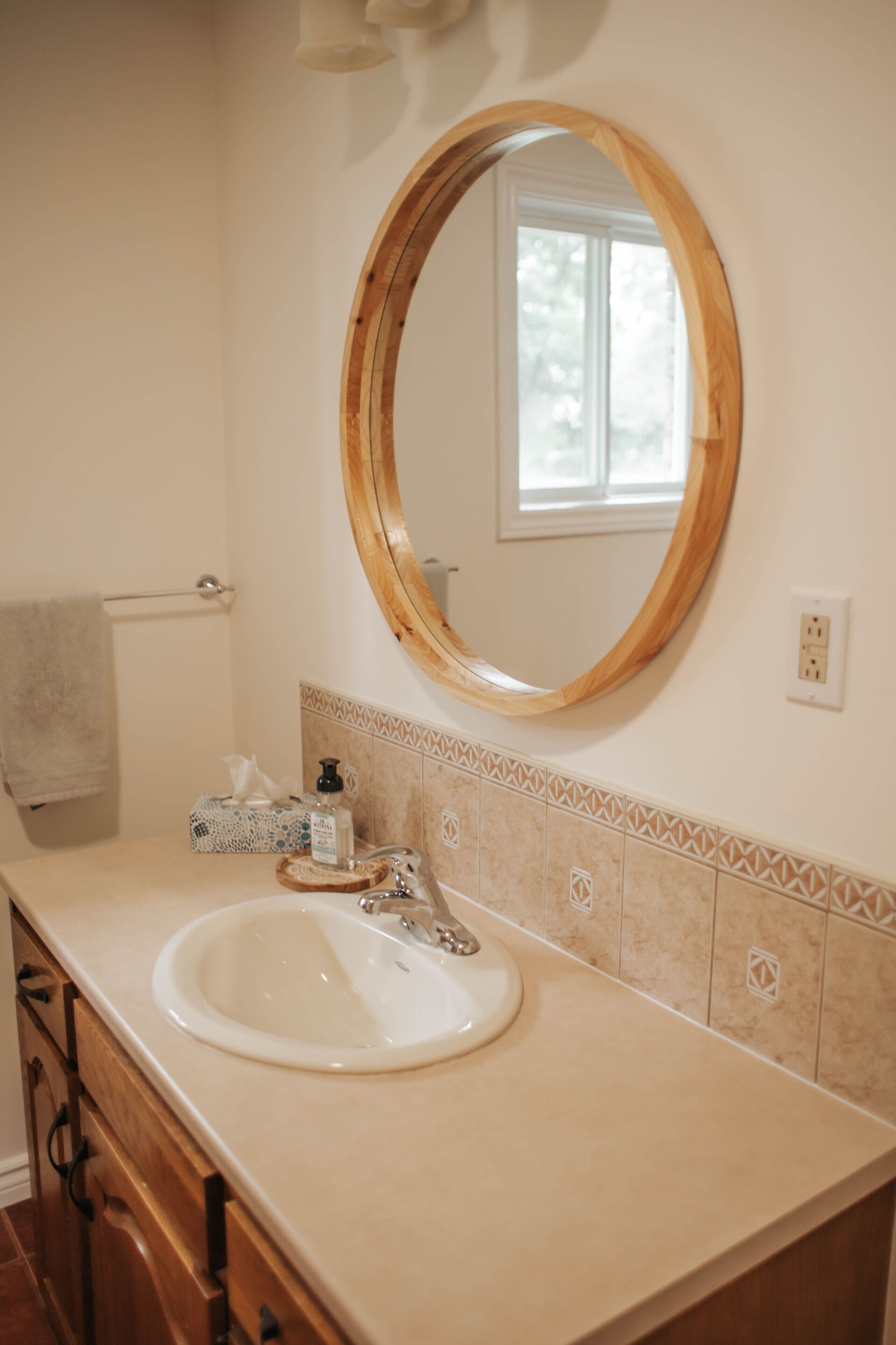 Une salle de bain avec un miroir à cadre en bois, un lavabo blanc et un porte-serviettes.