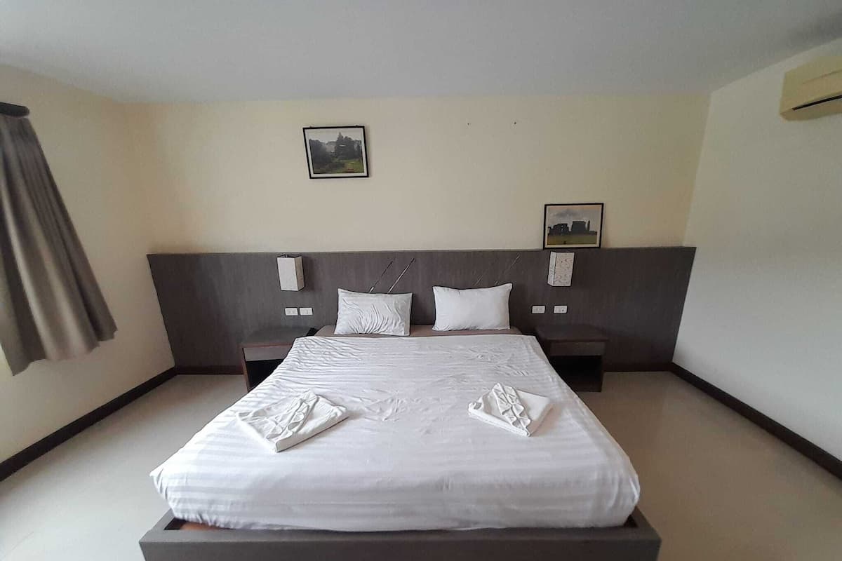 A modern hotel room with a large bed, two bedside tables, and a headboard with wall-mounted lights.
