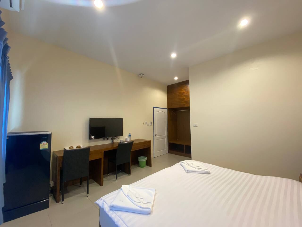 Une chambre d’hôtel comprenant un lit, un bureau avec une chaise, une télévision et une armoire.