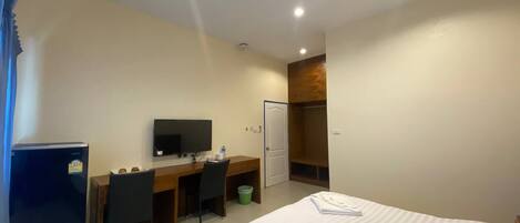 Una habitación de hotel con cama, escritorio, silla, televisor y armario.