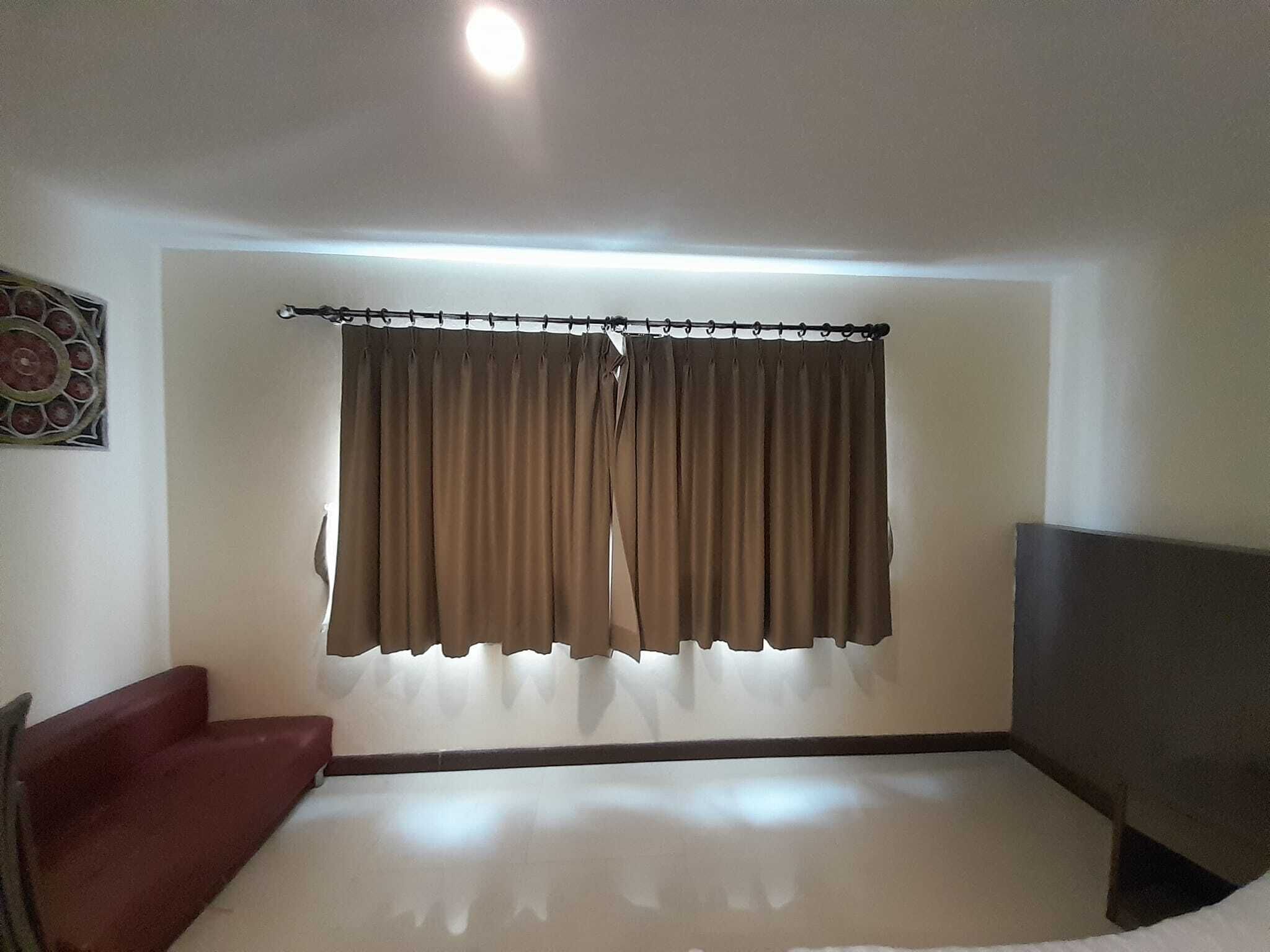 Una habitación con una cama grande, un televisor y una cortina.