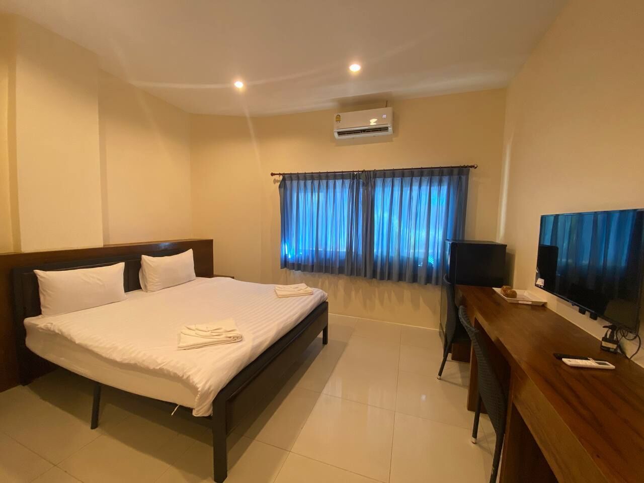 Een hotelkamer met een bed, een bureau, een televisietoestel en een airconditioning.