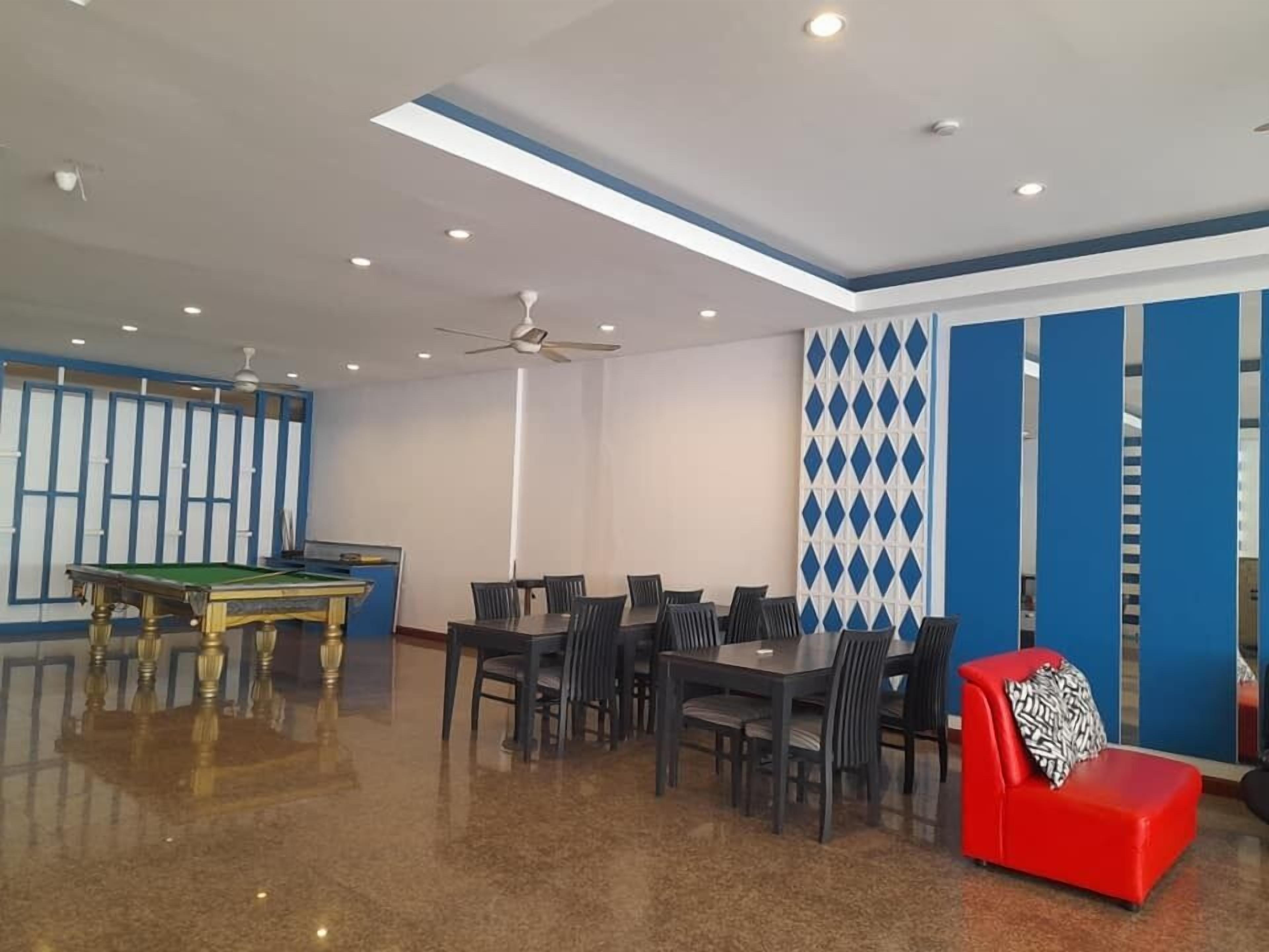 A room with a pool table, a red sofa, and a dining area with chairs.