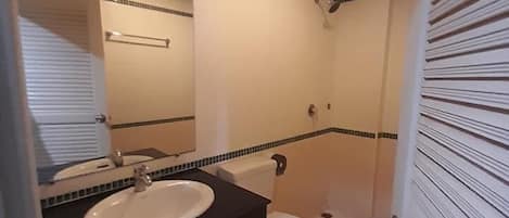 A bathroom with a sink, toilet, and shower.