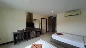 Quarto de hotel com cama, escrivaninha com televisão, espelho e guarda-roupa.
