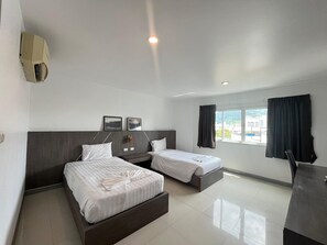 A hotel room with two beds, a desk, and a window with curtains. - Cocoon Patong Hotel (Patong)