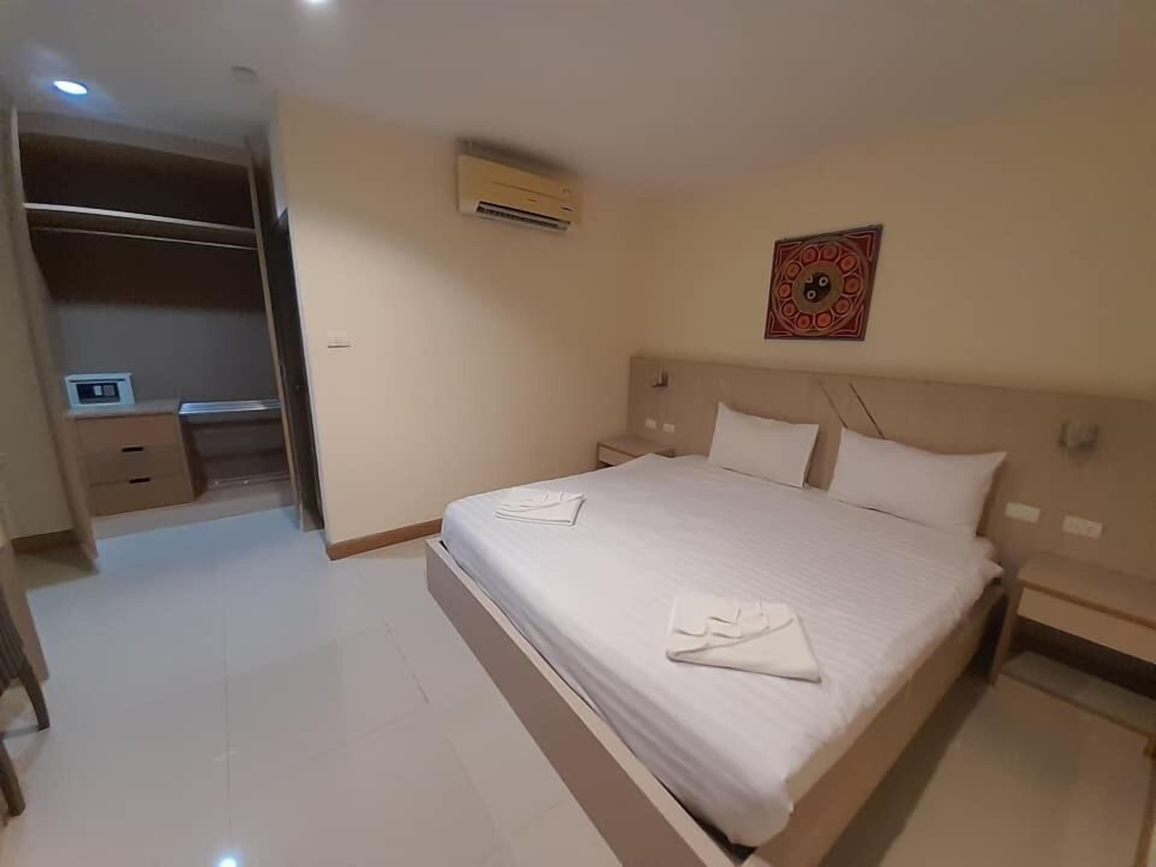 A hotel room with a large bed, a desk, and a wardrobe.