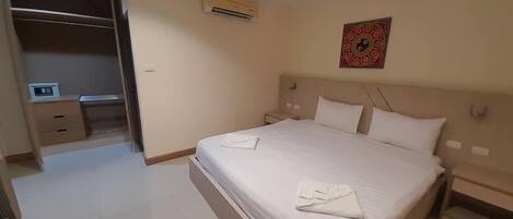 A hotel room with a large bed, a desk, and a wardrobe.