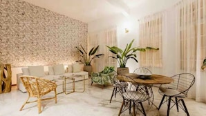 A modern living room with a stone wall, a sofa, a coffee table, and a dining area with chairs and a table. - Contemporary Flat inside the old City (Cartagena de Indias)