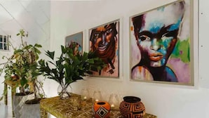 A hallway with a decorative table, potted plants, and three framed artworks on the wall. - Contemporary Flat inside the old City (Cartagena de Indias)