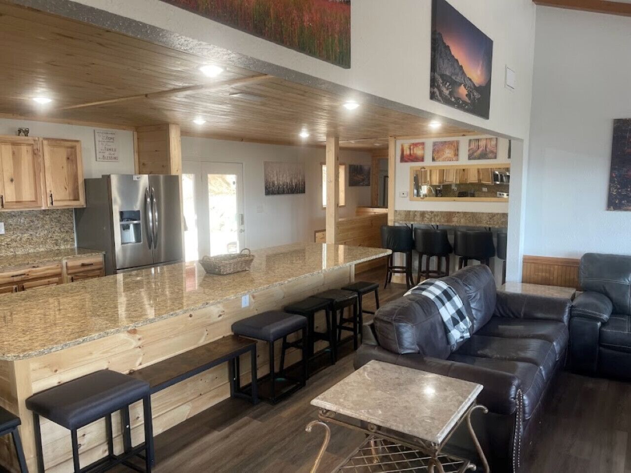 A modern kitchen with a granite countertop, wooden cabinets, and a stainless steel refrigerator.