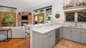A modern kitchen with grey cabinets, a marble countertop, and a stone fireplace. - Beautiful Mountain Home With Hot Tub on Free Bus Route (Vail)