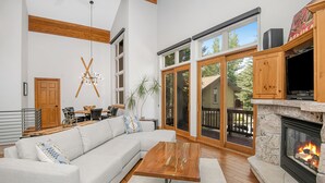 A modern living room with a sectional sofa, a wooden coffee table, a fireplace, and large sliding glass doors leading to a deck. - Beautiful Mountain Home With Hot Tub on Free Bus Route (Vail)
