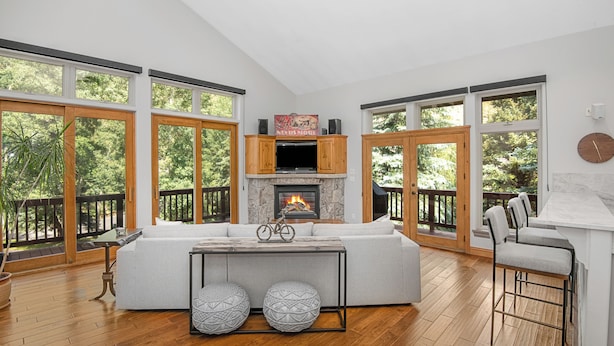 A spacious living room with a fireplace, large windows, a sofa, and a bar area. - Beautiful Mountain Home With Hot Tub on Free Bus Route (Vail)