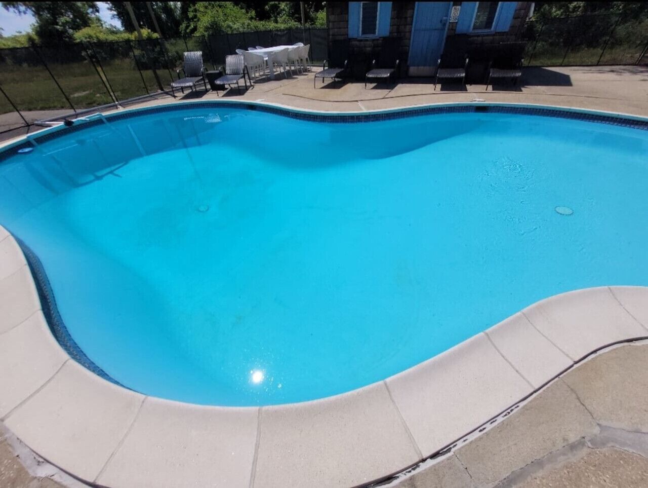 A swimming pool with a curved edge, surrounded by a tiled deck.