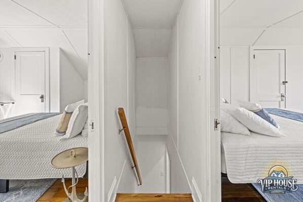 Een hotelkamer met een bed, een bureau en een stoel. Er is een deur die naar een andere kamer leidt.