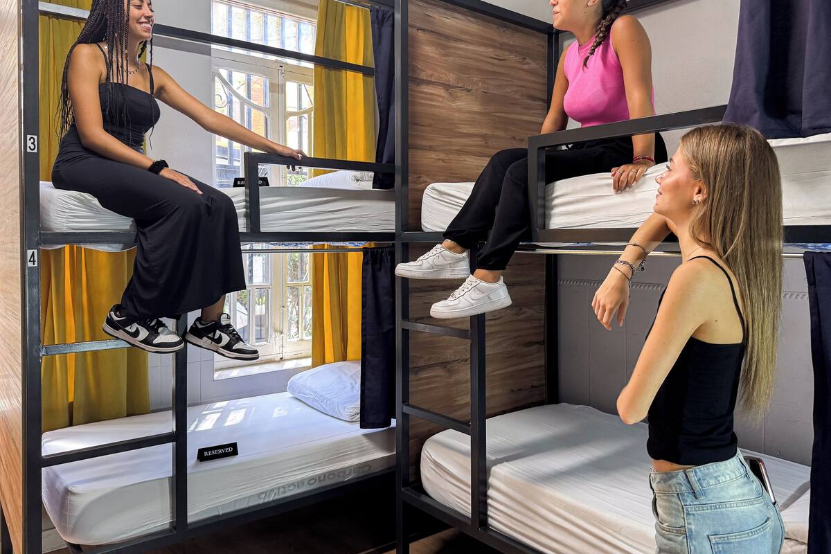 Quarto com beliche triplo, cortinas amarelas e vista para o exterior.