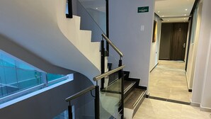 Una escalera moderna con barandillas de vidrio y un cartel que indica 'Escaleras'.