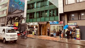 Vista de una calle con una camioneta blanca, un mural en un edificio y una tienda con un letrero que dice "Chantilly".