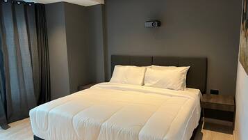 Quarto moderno com cama grande, paredes escuras e projetor no teto.