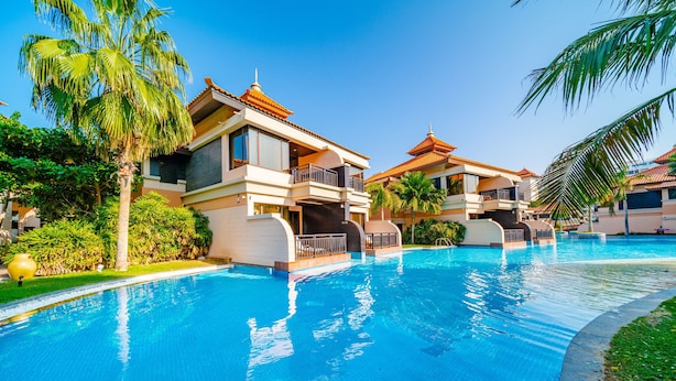 Un resort con piscina, palmeras y arquitectura moderna.