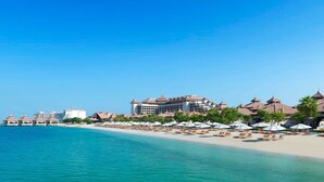 Een strandhotel met meerdere gebouwen, een zandstrand en parasols.