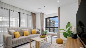 Een moderne woonkamer met een bank, salontafel en een groot raam met uitzicht op een gebouw.