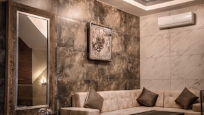 Una sala de estar moderna con un sofá color beige, un espejo grande y un reloj decorativo en la pared.