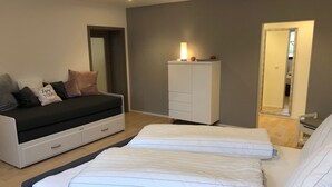 Quarto moderno com sofá, duas camas, guarda-roupa e espelho.