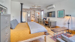 A bedroom with a bed, a desk, a chair, a wardrobe, and a brick wall. - The Brick Unit B on F st Downtown Salida! (Salida)