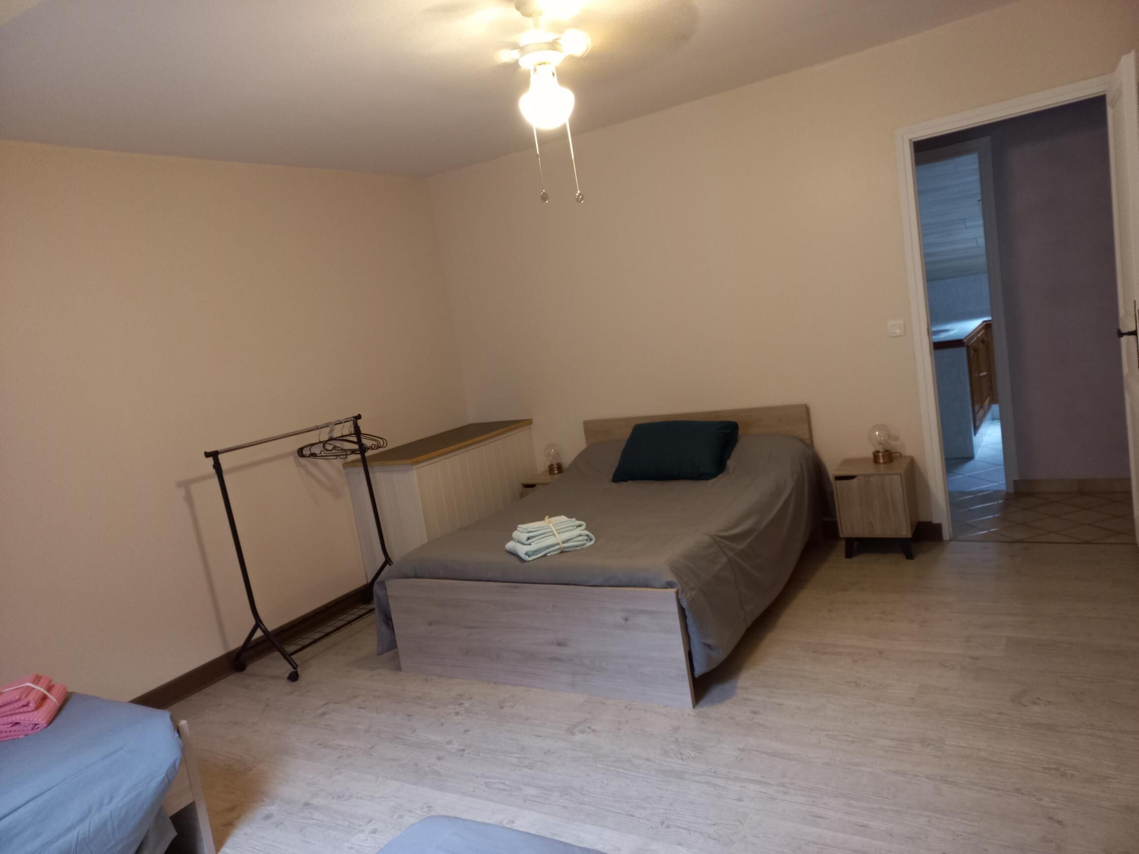 Une chambre à coucher comprenant un lit, une table de chevet, une commode, un radiateur et un ventilateur de plafond.