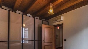 A bedroom with a bed, a wardrobe with sliding doors, a wooden ceiling, and a hanging light fixture.