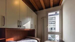 A bedroom with a wooden headboard, a bed, and a window with a view of a building.