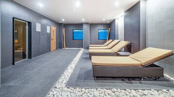 Relax in a serene spa area with lounge chairs, a flat-screen TV, and textured panels.