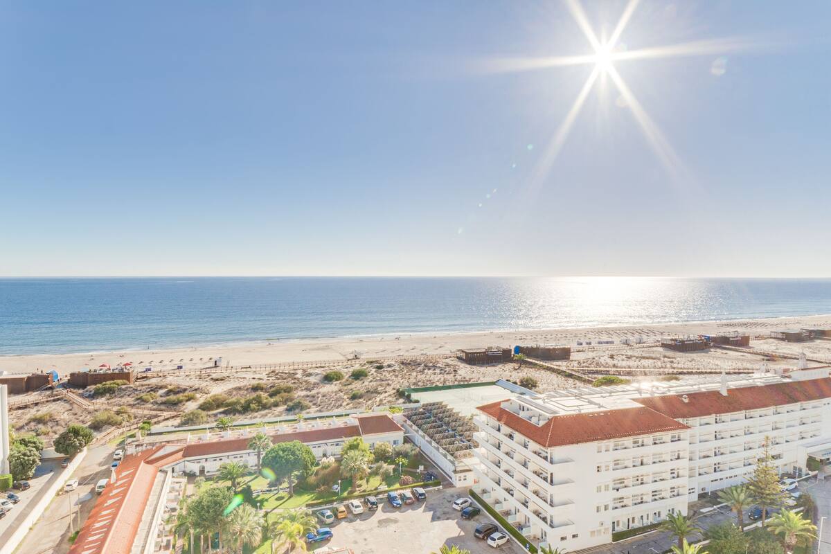 Un hotel costero de varios pisos, con estacionamiento y vistas a la playa.