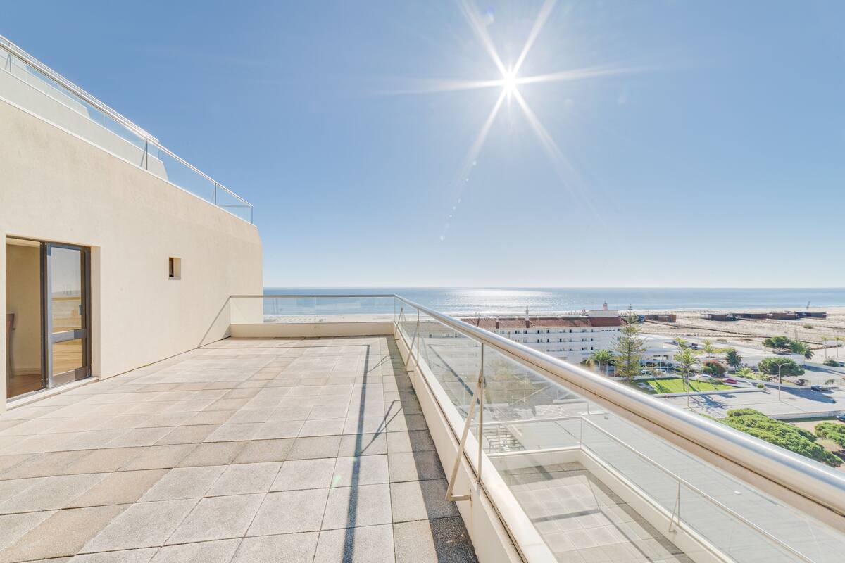 Una terraza en la azotea con vistas despejadas al mar y edificios a lo lejos.