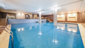 An indoor swimming pool with clear water, a metal ladder, and a staircase leading to a higher level. - Yellow Praia Monte Gordo (Vila Real Santo Antonio)