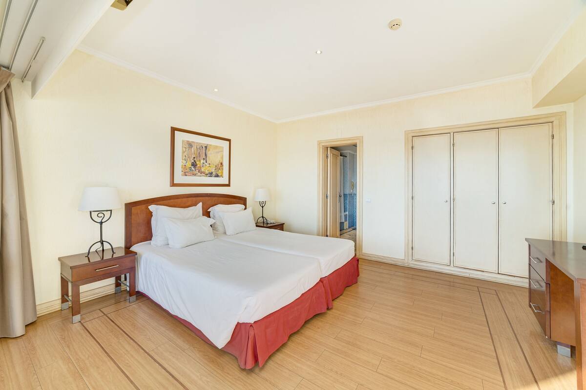 Una habitación de hotel con una cama grande, una mesita de noche, un escritorio y un armario.