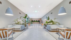 A spacious lobby with a central reception desk, seating areas with sofas and tables, and potted plants. - Yellow Praia Monte Gordo (Vila Real Santo Antonio)