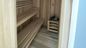 Eine Holzsauna mit drei Bänken und einer kleinen Ablage.