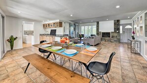 Une cuisine spacieuse avec un coin repas, comprenant une longue table en bois pouvant accueillir quatre personnes, un four encastré et un mur décoratif en pierre.
