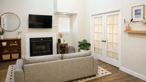 A living room with a fireplace, a sofa, a television, and a door with glass panels.