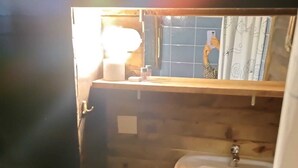 A compact bathroom with a wooden bench, a sink, and a mirror. - Kulindağ Dağ Evi (Beykoz)