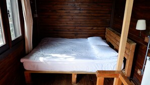 A wooden cabin room with a bed, a window with curtains, and a wooden headboard. - Kulindağ Dağ Evi (Beykoz)