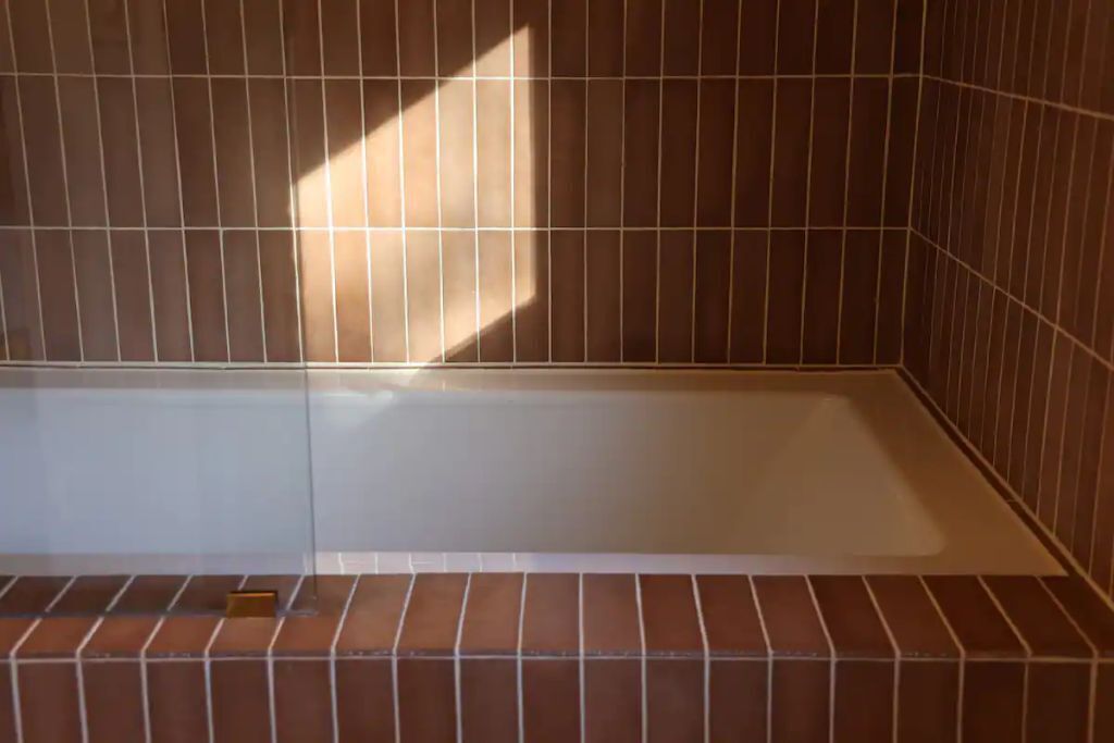A tiled bathroom with a shower area and a visible drain.