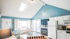 A compact living space with a dining area, kitchenette, and a large window providing natural light. - Seawinds II (Dennis Port)